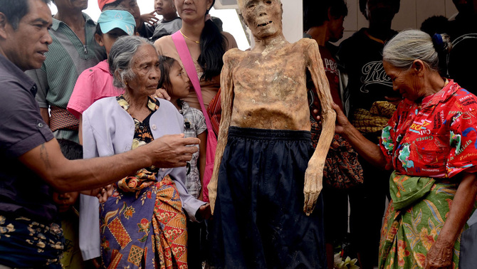 Sejumlah anggota keluarga mengenakan pakian ke jenazah Piter Sampe Sambara yang meninggal dunia pada 80 tahun lalu saat ritual adat Ma'nene' di Gunung Sesean, Lembang Lempo Boton, Kec. Rinding Allo, Toraja Utara, Sulawesi Selatan. FOTO: EPA/ANDI SAMUDRA