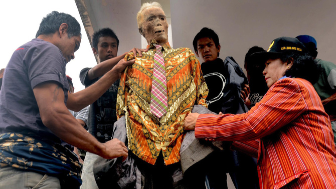 Anggota keluarga mengenakan pakian ke jenazah Piter Sampe Sambara yang meninggal dunia pada 80 tahun lalu saat ritual adat Ma'nene' di Gunung Sesean, Lembang Lempo Boton, Kec. Rinding Allo, Toraja Utara, Sulawesi Selatan. FOTO: EPA/ANDI SAMUDRA