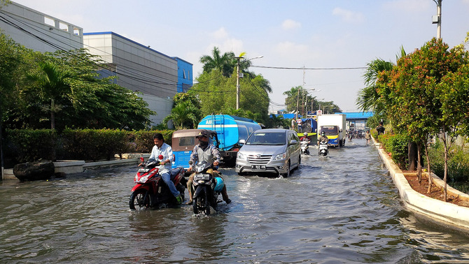 Sejumlah pengendara berusaha menerobos genangan air rob di kawasan Pelabuhan Perikanan Samudera Nizam Zachman Muara Baru, Kelurahan Penjaringan, Kecamatan Penjaringan, Jakarta Utara, 7 Juni 2016.