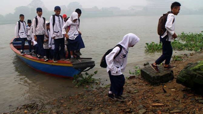 Sejumlah warga dan anak sekolah turun dari perahu sebagai alat transportasi menuju ke sekolah di tepian sungai Musi, Palembang, Sumatra Selatan, 30 Oktober 2015.