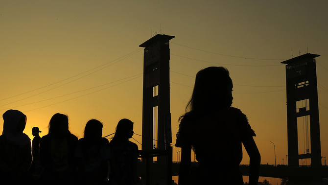 Sejumlah remaja menikmati pagi pertama bulan Ramadan di atas Jembatan Ampera Palembang, 6 Juni 2016. Kegiatan yang dikenal dengan istilah 