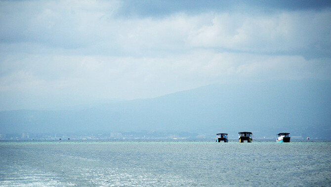 Sejumlah kapal wisatawan melintas di perairan Taman Nasional Laut Bunaken dengan latar belakang kota Manado, Sulawesi Utara, 31 Maret 2016. FOTO: BeritaSatu Photo/Danung Arifin