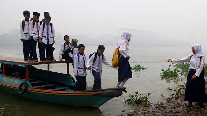Sejumlah warga dan anak sekolah turun dari perahu sebagai alat transportasi menuju ke sekolah di tepian sungai Musi, Palembang, Sumatra Selatan, 30 Oktober 2015.