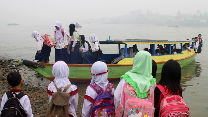 Sejumlah warga dan anak sekolah menunggu perahu sebagai alat transportasi menuju ke sekolah di tepian sungai Musi, Palembang, Sumatra Selatan, 30 Oktober 2015.