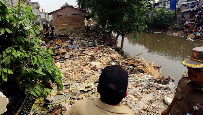 Petugas mengawasi alat berat yang bekerja dalami penggusuran di kawasan kampung Pulo, Jatinegara, Jakarta Timur, 20 Agustus 2015.