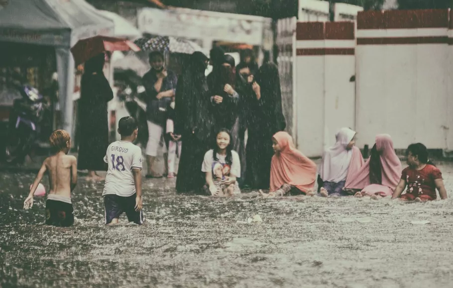 Anak-anak bermain di jalan yang tergenang banjir dikawasan kolong flyover Tebet, Jakarta Selatan, Kamis 18 Februari 2021.