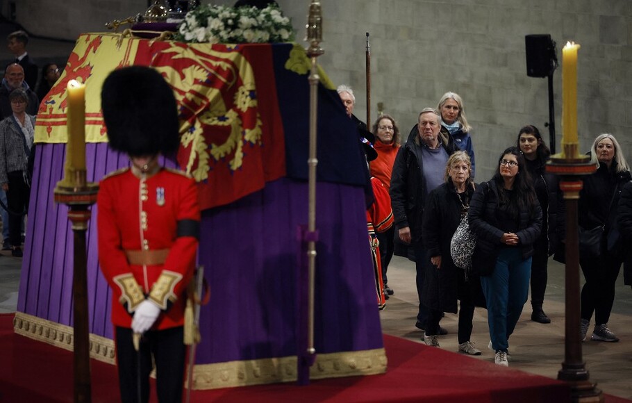 Warga Inggris berjalan melewati peti mati Ratu Elizabeth II yang terbungkus bendera di catafalque, Westminster Hall di tengah malam pada Sabtu 17 September 2022 dini hari.