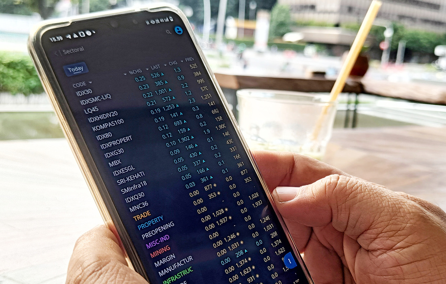 Investor memantau saham menggunakan telepon seluler di Jakarta.