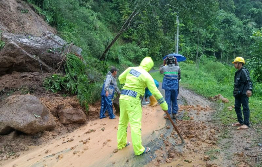 Polisi dan masyarakat berupaya menyingkirkan material longsoran tanah dan bebatuan yang menutupi badan jalan di Pamulihan, Kabupaten Garut, Jawa Barat.