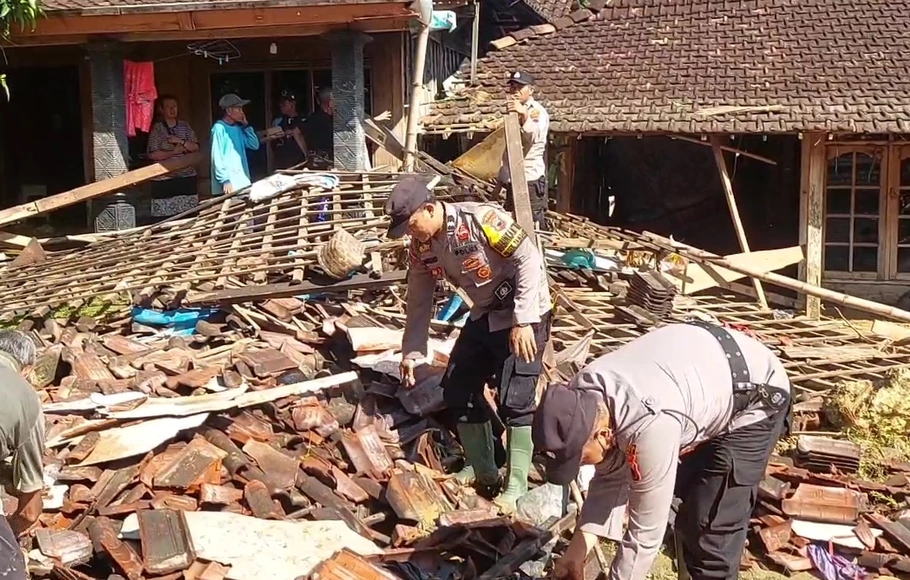 Aparat kepolisian membantu warga membersihkan puing reruntuhan rumah yang ambruk diterjang banjir bandang di Desa Sinomwidodo, Tambakromo, Pati, Jateng, Kamis, 1 Desember 2022. 