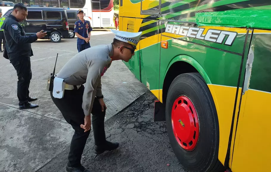 Seorang polisi melakukan ramp check atau melakukan pemeriksaan kelayakan bus angkutan Lebaran di Terminal Kertawangunan, Kuningan, Jawa Barat, Rabu, 12 April 2023.