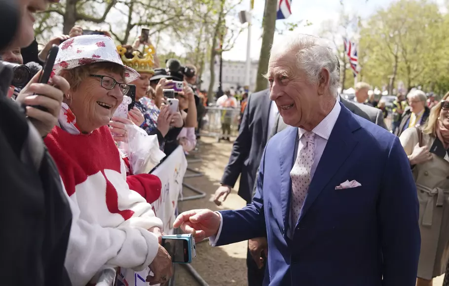 Raja Inggris Charles III menyapa warga yang berada di luar Istana Buckingham, London, Jumat, 5 Mei 2023, sehari sebelum penobatannya.