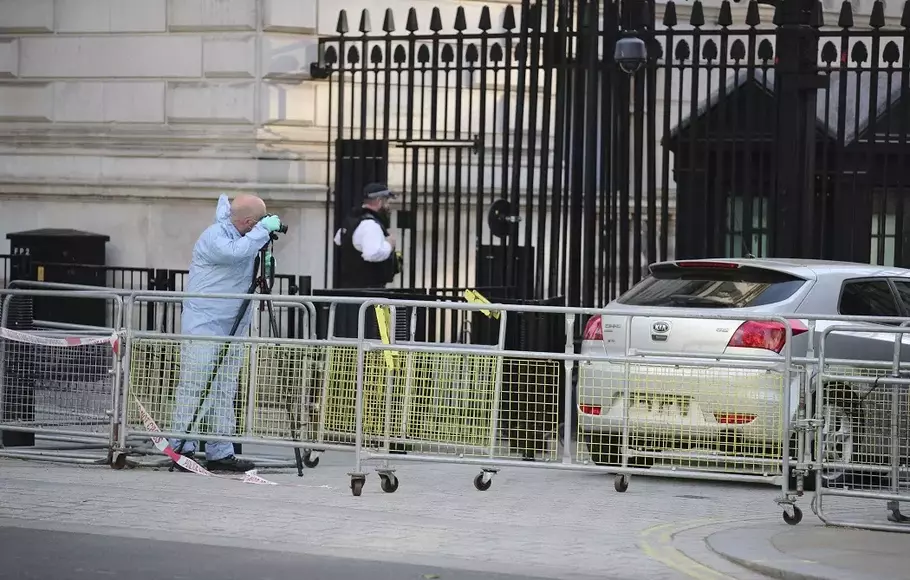Seorang petugas forensik memotret mobil yang menabrak gerbang Downing Street di London, Kamis 25 Mei 2023.