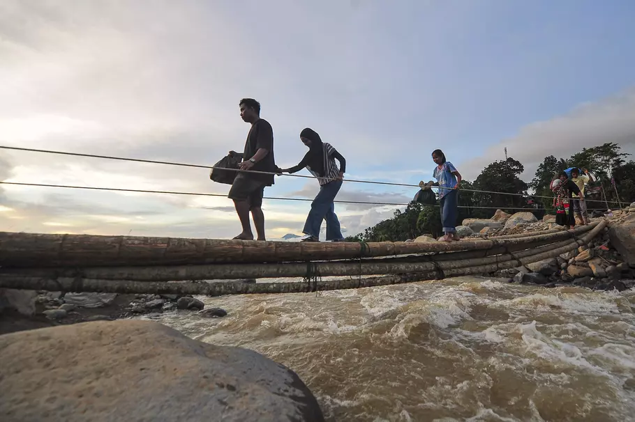 Warga menyeberangi jembatan darurat di atas aliran Sungai Nanggang di Nagari Salareh Aia Timur, Palembayan, Agam, Sumatera Barat. - (Antara/Wahdi Septiawan)