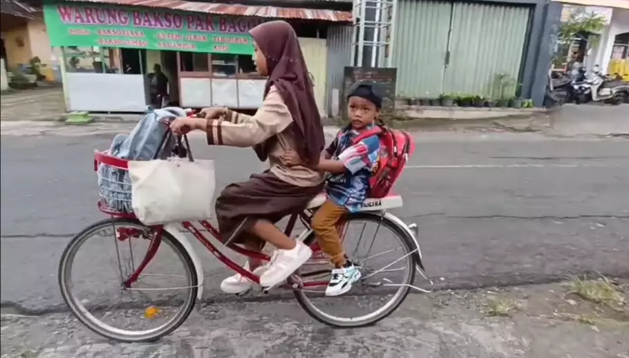 Ariendra Raela Irgantari membonceng adiknya Reyfan Elcaraka Fahturohman saat pulang sekolah. - (Beritasatu.com/Olena Wibisana)