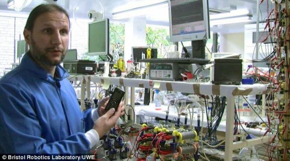 Dr Ioannis Ieropoulos memegang sebuah ponsel yang ditenagai urin di Bristol Robotics Laboratory.