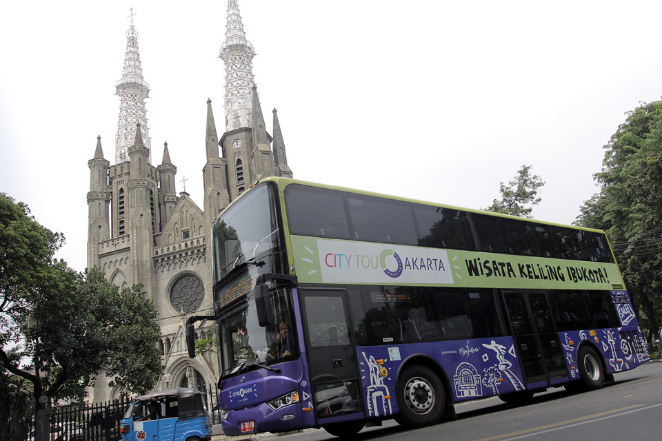 Bus tingkat wisata Ibukota melintas di depan Gereja Katedral Jakarta.