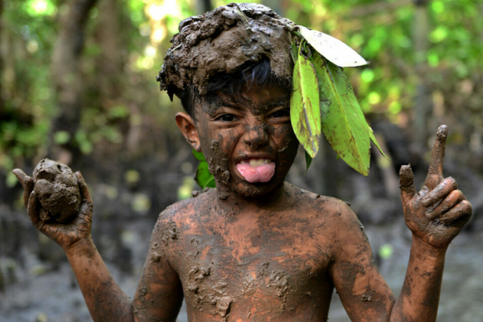 Seorang anak Bali berpose sambil melumuri tubuhnya dengan lumpur saat melaksanakan tradisi 
