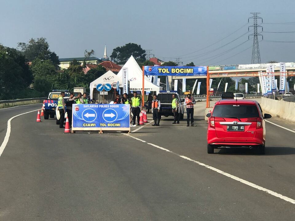 Petugas Polres Bogor memasang spanduk dan membantu mengarahkan kendaraan pribadi yang akan melintas Ciawi menuju Sukabumi melalui ruas tol fungsional Bocimi, Minggu, 10 Juni 2018.
