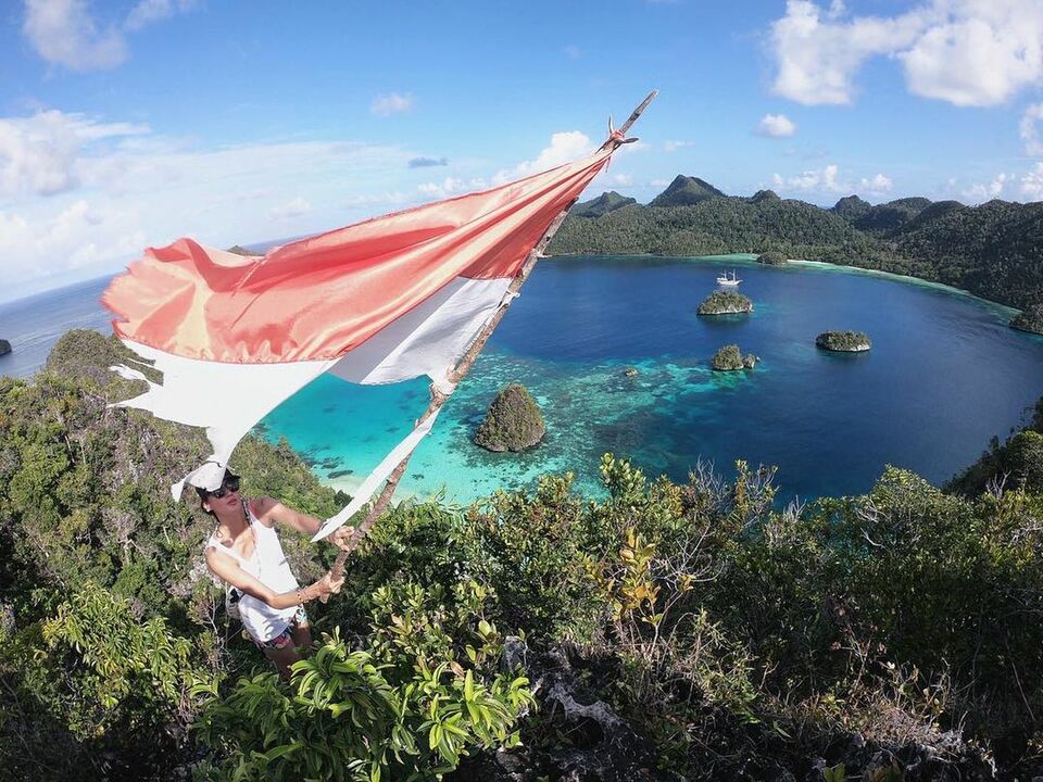 Nadine menngibarkan bendera Indonesia yang robek di Puncak Wayag, Raja Ampat, Papua Barat.