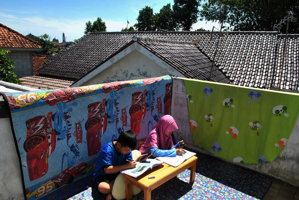Siswa SD mengerjakan tugas sekolah menggunakan aplikasi daring dari gawai sambil berjemur sinar matahari pagi di rumahnya, di Laladon Gede, Desa Laladon, Ciomas, Kabupaten Bogor, Jawa Barat, belum lama ini. 

