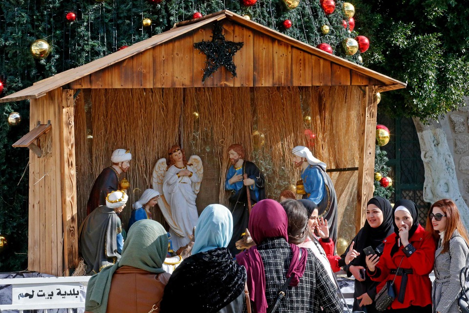Warga Palestina melihat dekorasi Natal di luar Church of the Nativity  di Betlehem.