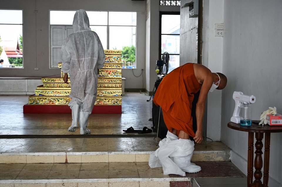 Seorang biksu melepas alat pelindung diri seusai melakukan kremasi bagi korban Covid-19, di Wat Chin Wararam Worawihan, Bangkok, 30 Juli 2021.