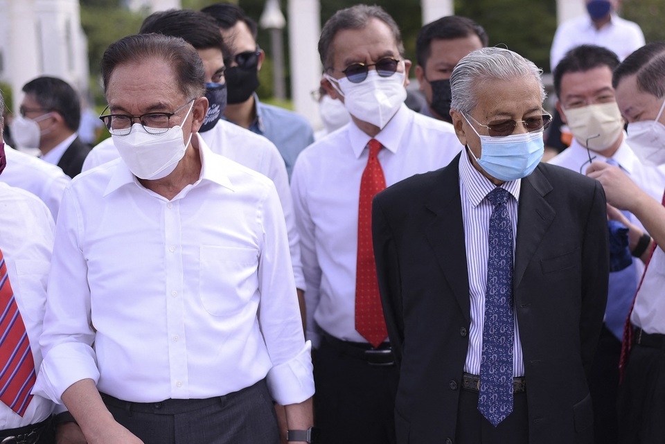 Mantan Perdana Menteri Malaysia Mahathir Mohamad (kanan) dan anggota parlemen oposisi Anwar Ibrahim (kiri) berbaris di depan sebagai protes di depan gedung parlemen yang ditutup di Kuala Lumpur pada 2 Agustus 2021. 