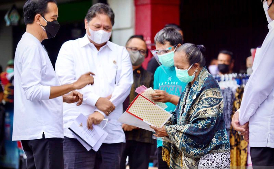 Presiden Joko Widodo (kiri) didampingi Menteri Koordinator Bidang Perekonomian Airlangga Hartarto (tengah) saat memberikan secara simbolis bantuan tunai untuk pedagang kaki lima dan Warung (BT-PKLW) di kawasan Malioboro Yogyakarta, Sabtu 9 Oktober 2021.