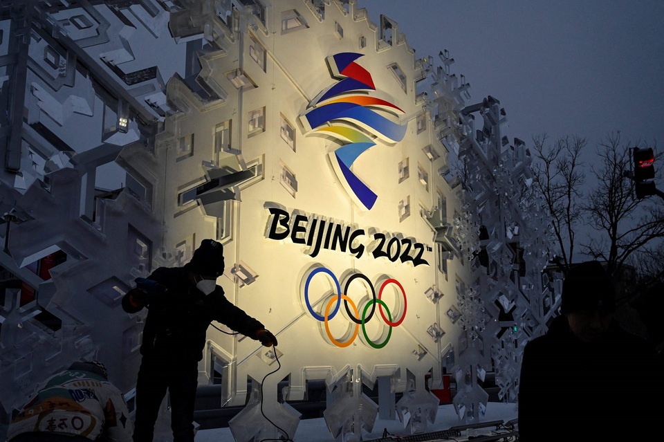 Para pekerja memasang instalasi yang memajang logo Olimpiade Musim Dingin Beijing 2022 di sepanjang jalan di Beijing pada 21 Januari 2022. 
