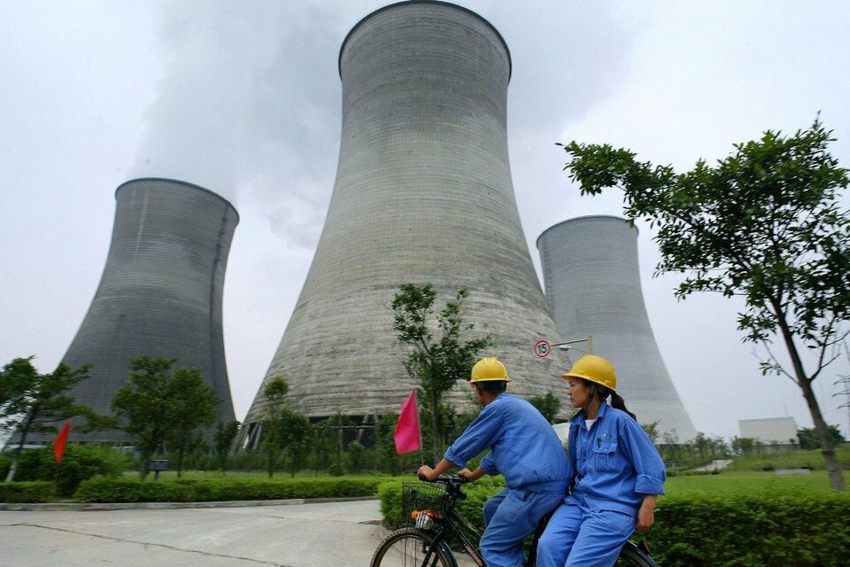 Sepasang karyawan melintas dekat pembangkit listrik tenaga nuklir Tiongkok.