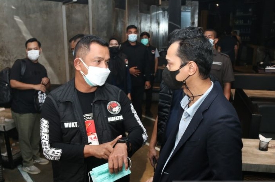Direktur Reserse Narkoba Polda Metro Jaya Kombes Pol Mukti Juharsa (kanan) menegur pengelola bar yang beroperasi melampaui batasan jam operasional yang ditetapkan dalam kebijakan PPKM di Jakarta, Kamis 3 Februari 2022. 
