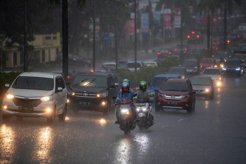 Pengendara menerobos hujan lebat saat melintas di jalan protokol Palembang, Sumatera Selatan.