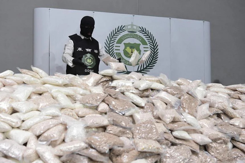 Seorang petugas keamanan Arabb Saudi menumpuk kantong pil amfetamin di satu gudang di lokasi yang dirahasiakan pada 31 Agustus 2022.