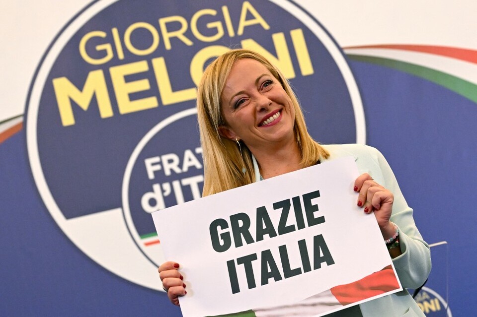 Pemimpin sayap kanan Italia dari partai Brothers of Italy, Giorgia Meloni memegang plakat bertuliskan 