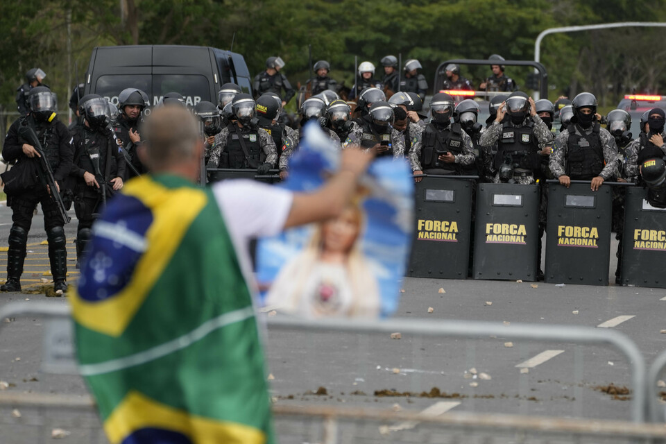 Seorang pengunjuk rasa, pendukung mantan Presiden Brasil Jair Bolsonaro, diadang barisan polisi setelah para demonstran menyerbu Istana Planalto di Brasilia, Brasil, Minggu, 8 Januari 2023.