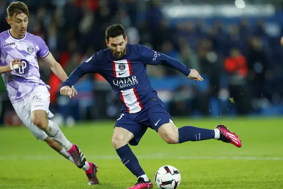 Lionel Messi berusaha melewati adangan pemain Toulouse.