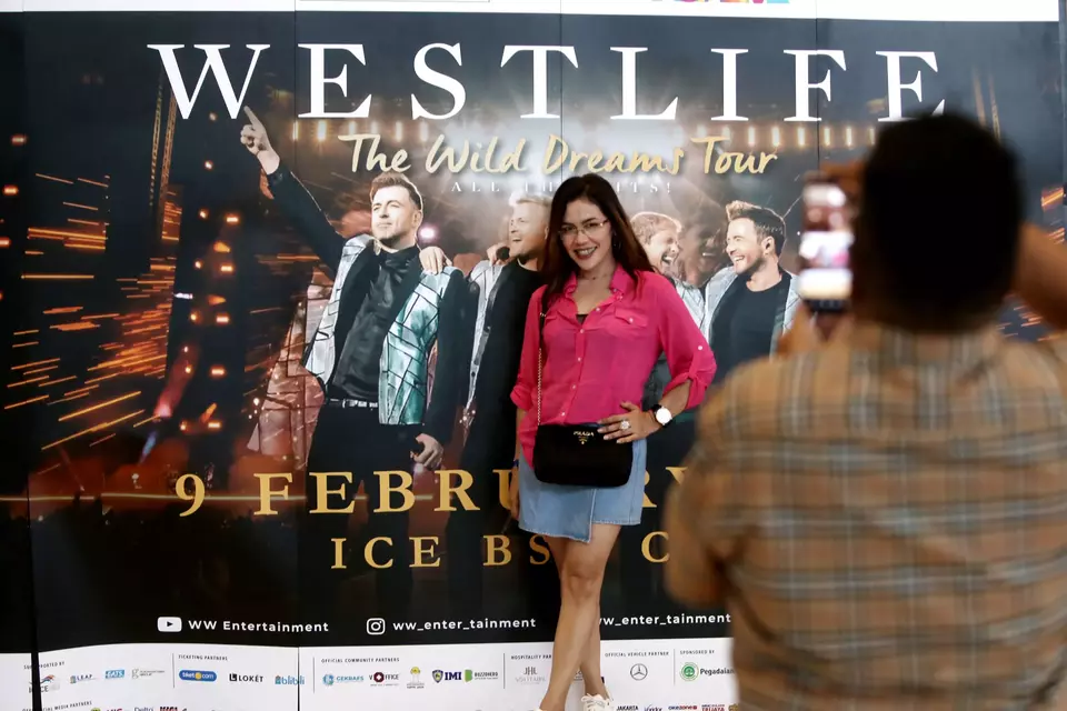 Calon penonton boyband Westlife berpose dengan latar group vokal tersebut sebelum menyaksikan konser Westlife The Wild Dreams Tour di ICE BSD City, Tangerang, Banten, Kamis, 9 Februari 2023.