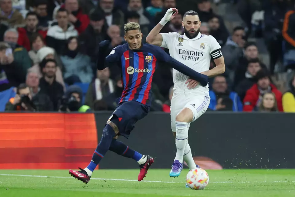Pemain Barcelona, Raphinha (kiri), berduel dengan striker Real Madrid, Karim Benzema.