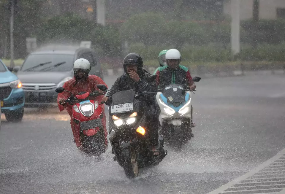Pengendara sepeda motor melintas saat hujan deras.