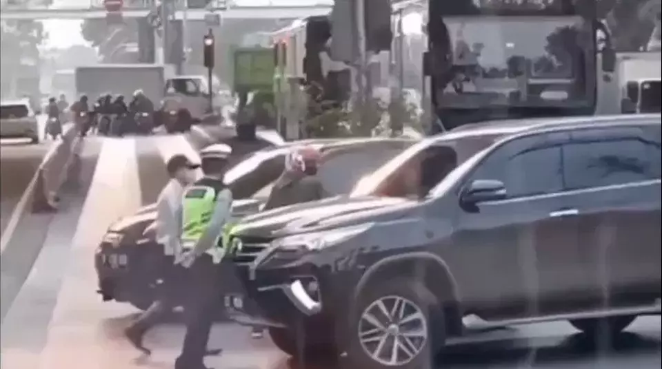 Aksi arogan pengemudi Fortuner nyaris menabrak anggota polisi lalu lintas, di lampu merah perempatan Cengkareng, Jakarta Barat, Senin (20/3/2023).