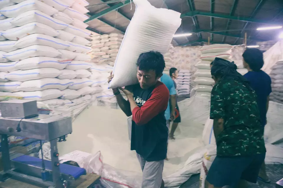 Pekerja memanggul beras dari dalam karung saat bongkar muat di Pasar Beras Beras Cipinang, Jakarta Timur, Minggu (26/3/2023).