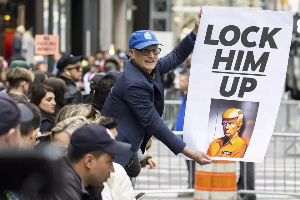Seorang pengunjuk rasa memegang poster bergambar Donald Trump di luar Trump Tower di New York pada hari Senin, 3 April 2023.