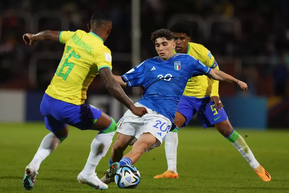 Penyerang Italia, Simone Pafundi (tengah), berupaya melewati pemain Brasil Marquinhos (kiri) dan Andrey Santos dalam partai penyisihan Grup D di Piala Dunia U-20 di Stadion Mendoza, Argentina, Sabtu, 12 Mei 21, 2023.