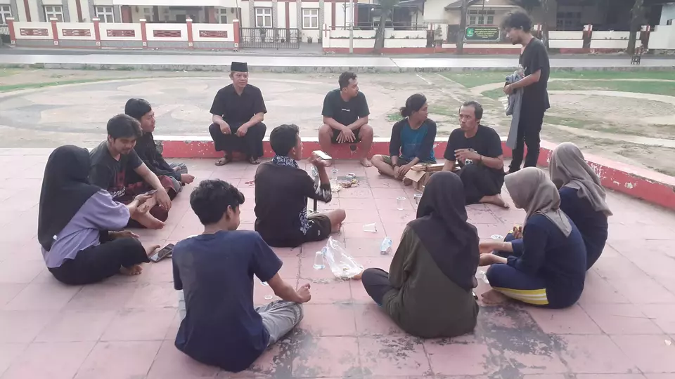 Ketua Dewan Kesenian Sumenep KH Turmidzi Jaka (songkok hitam) sedang mengajar mahasiswa berlatih teater di lapangan Gotong-Royong, Kota Sumenep, Jawa Timur, Minggu, 18 Juni 2023.