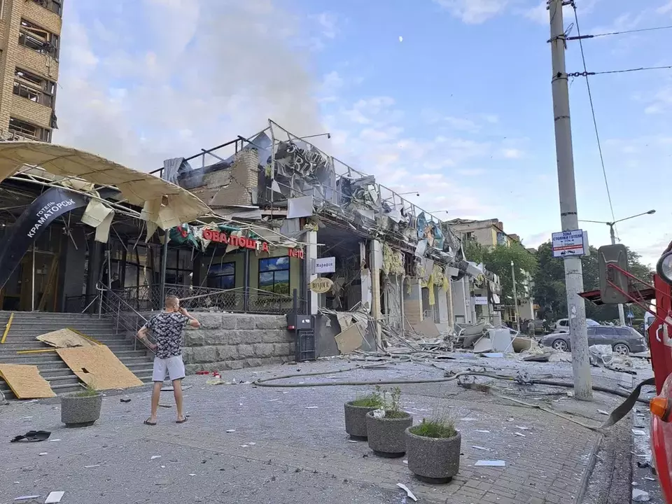 Seorang pria berdiri di jalan di depan toko dan restoran RIA Pizza yang hancur akibat serangan Rusia di Kramatorsk, Ukraina, Selasa, 27 Juni 2023.