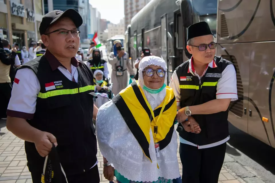 Petugas haji sedang membantu jemaah haji lansia.