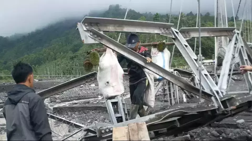 Warga Lumajang, Jawa Timur, nekat melintasi jembatan yang putus akibat diterjang banjir lahar Semeru, Minggu 9 Juli 2023.