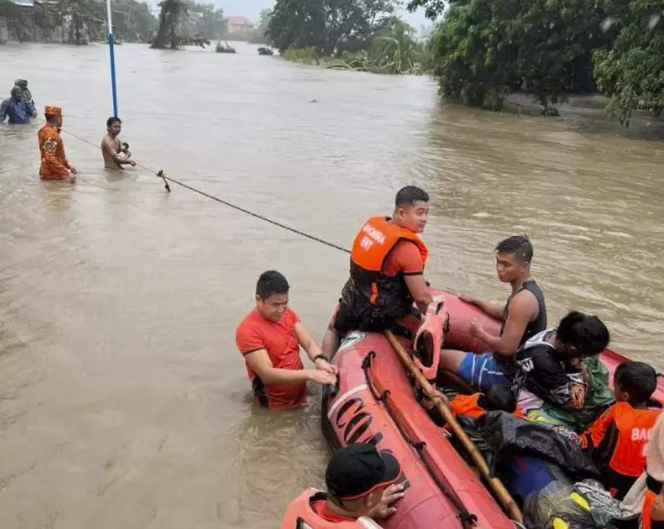 Regu penyelamat menggunakan perahu karet untuk mengevakuasi penduduk yang terjebak banjir di Bacarra, provinsi Ilocos Norte, setelah kawasan Filipina utara diterjang Topan Doksuri, Rabu, 26 Juli 2023.