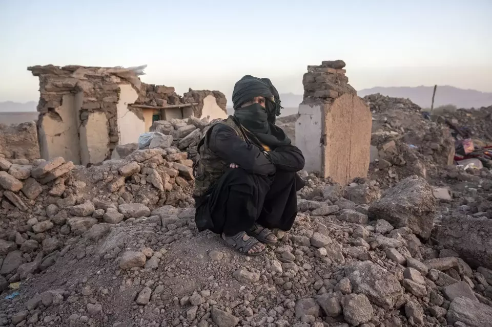 Warga Afganistan duduk di dekat reruntuhan rumahnya akibat gempa bumi di distrik Zenda Jan di provinsi Herat, Minggu, 8 Oktober 2023.